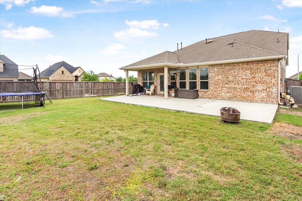 Large fenced backyard with extended patio, perfect for entertaining.