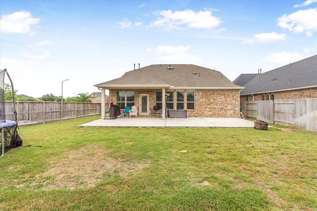 Large fenced backyard with extended patio, perfect for entertaining.