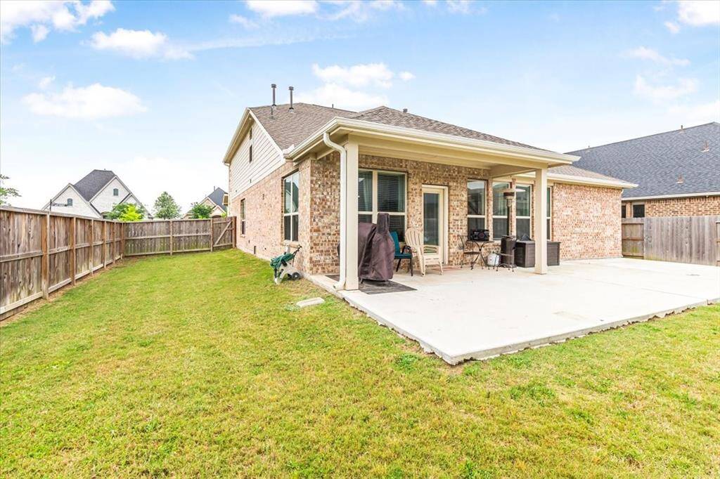 Large fenced backyard with extended patio, perfect for entertaining.