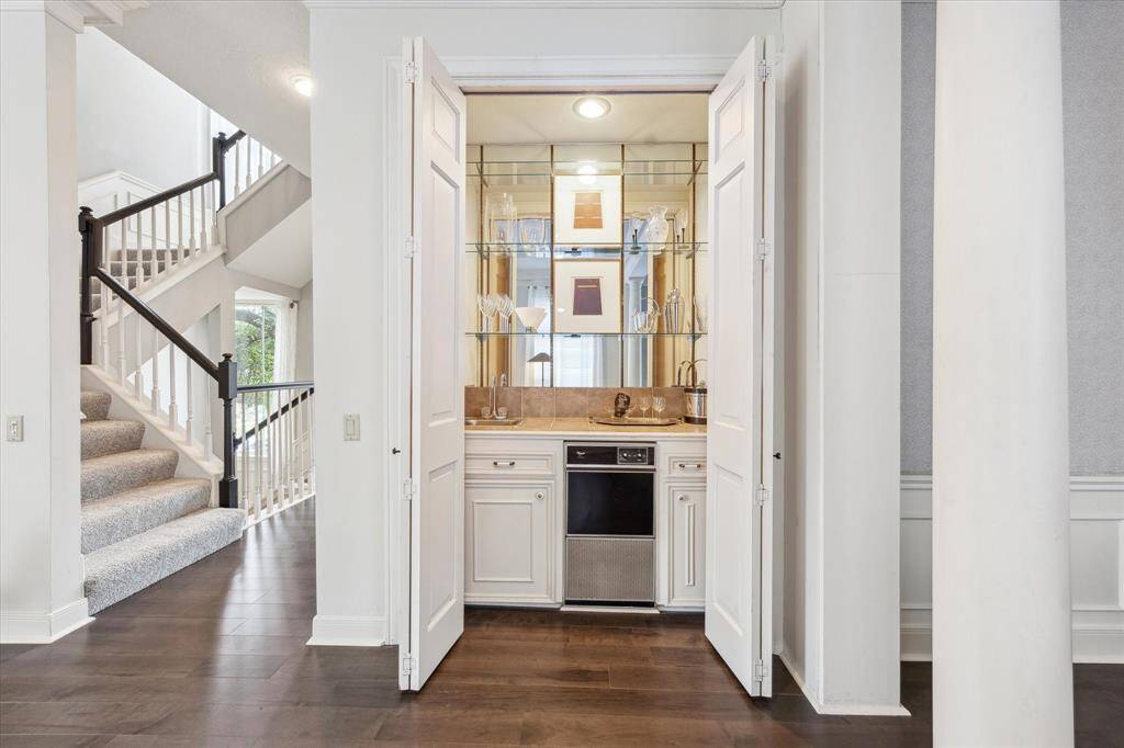 Stylish, mirrored wet bar with a small sink, glass shelving for elegant glassware, and a built-in icemaker...all perfect for entertaining in a home setting.