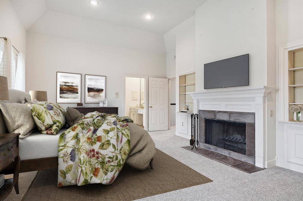 Virtually Staged Primary Bedroom with wood burning fireplace flanked by custom bookshelves with cabinets below.