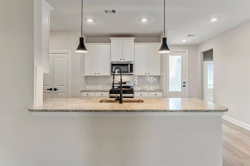 This spacious kitchen is a chef's dream. It has granite countertops, a full suite of stainless steel appliances, and a view of the family room. This open kitchen has a breakfast bar for casual dining and easy entertaining.