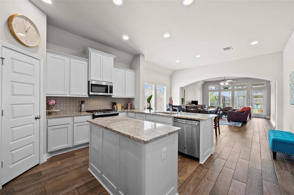 Entertain in style in this beautiful kitchen featuring granite countertops, white painted cabinets, a herringbone tile backsplash, and a large island!