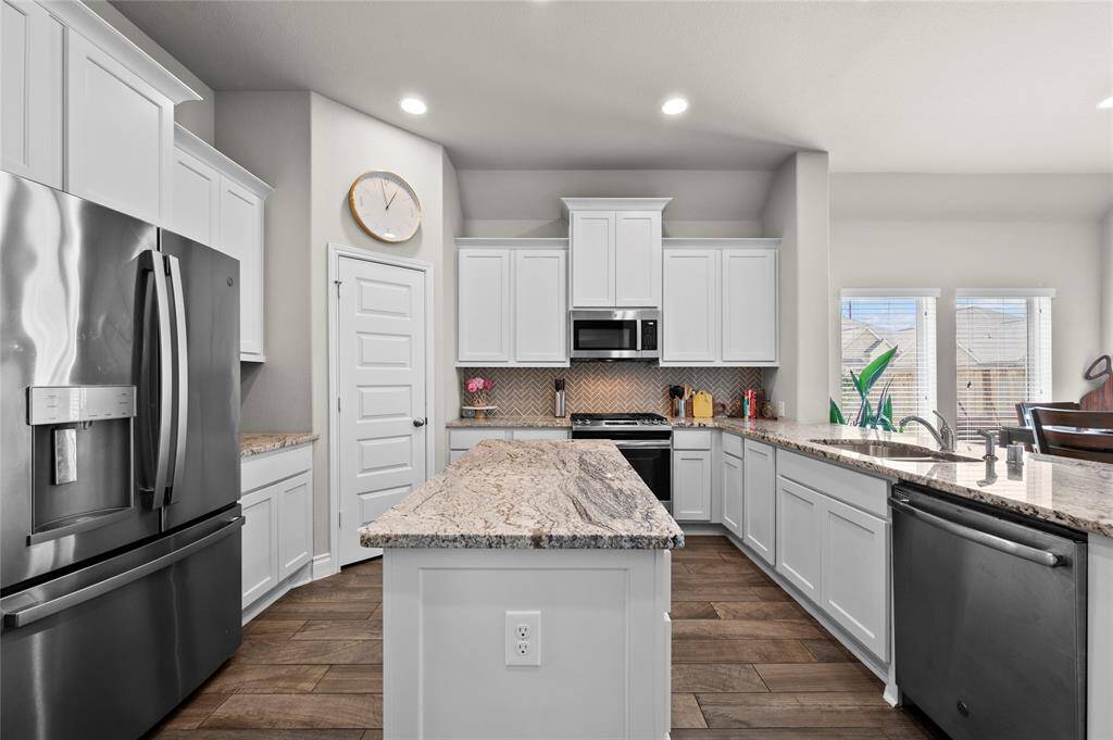 Entertain in style in this beautiful kitchen featuring granite countertops, white painted cabinets, a herringbone tile backsplash, and a large island!