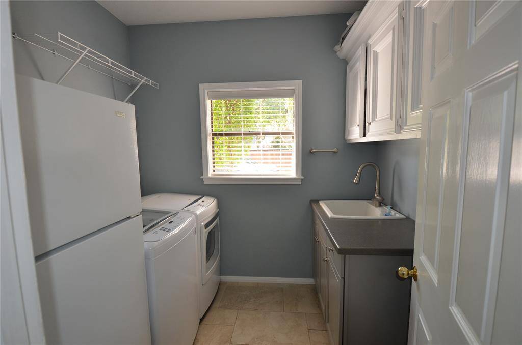 Large utility room features large sink with motion sense faucet and overhead storage