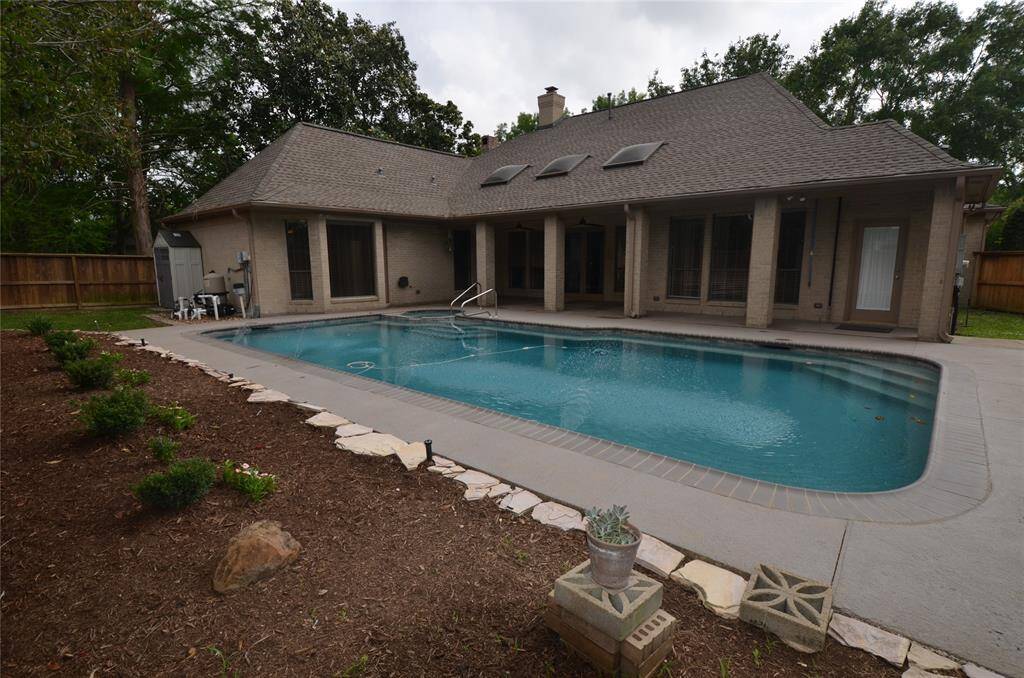 Large inground pool with spa connected to back patio and storage sheds