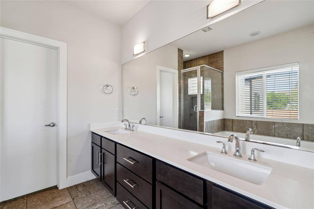 The ensuite bath features dual sinks, a soak in tub and a framed glass shower.