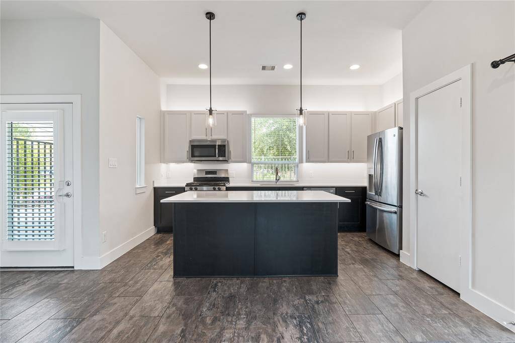 Another view of your kitchen with tons of natural light from your windows and pendant lighting over your island.