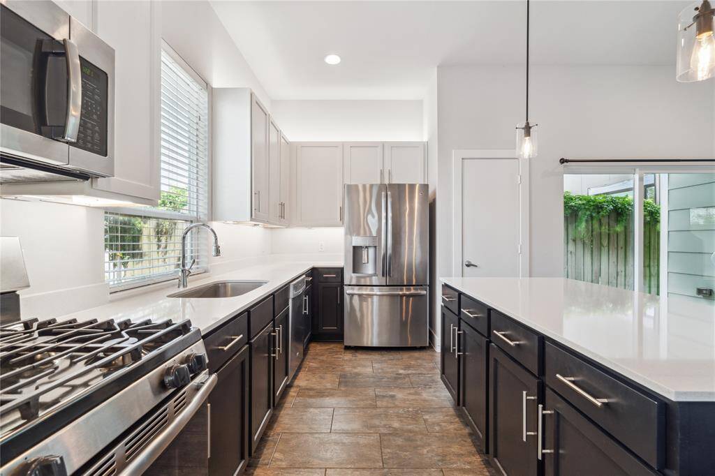 Equipped with stainless steel appliances including a fridge, and tons of kitchen storage.