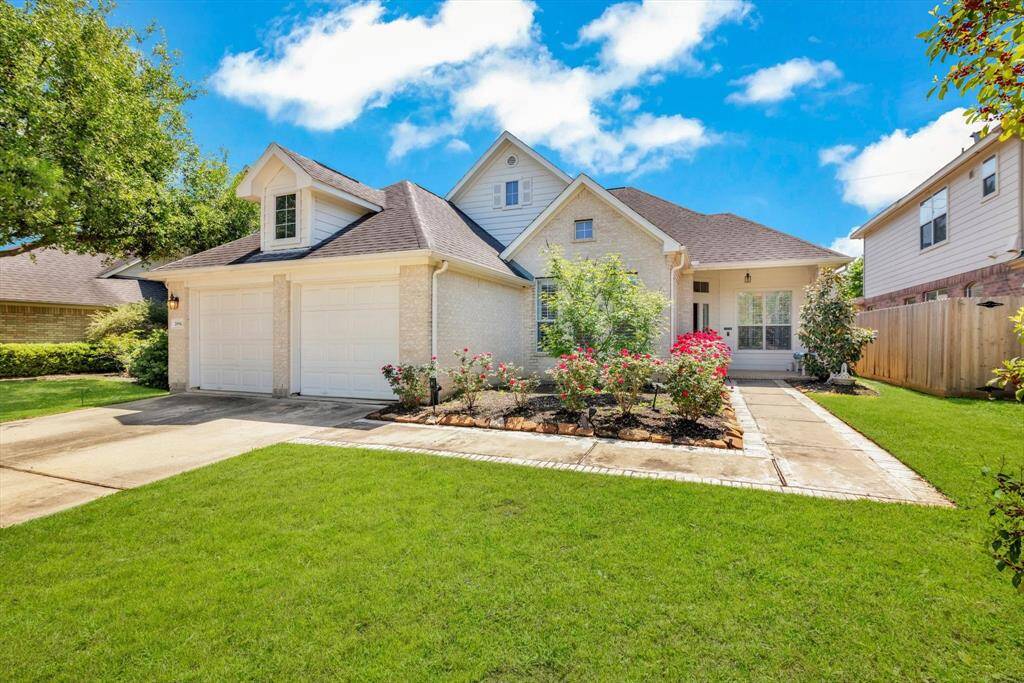 Charming single-story home with a two-car garage, well-maintained lawn, and a beautiful garden. The light brick exterior and peaked roof add to its curb appeal.