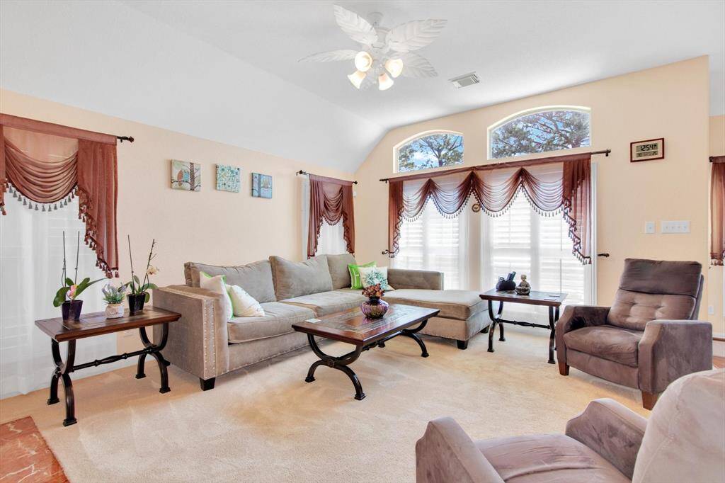 Bright and inviting living room with high ceilings and large windows. Features include elegant drapes creating a warm and comfortable atmosphere.