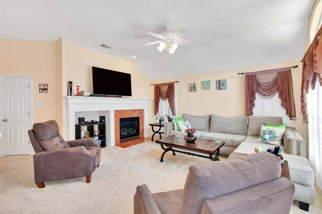Spacious living room with neutral tones, featuring a cozy fireplace.