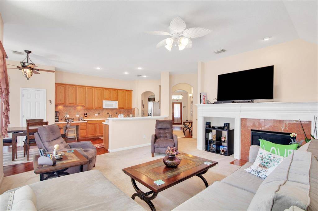 The open layout connects to a modern kitchen with wood cabinetry and a breakfast bar, enhancing the home's welcoming atmosphere.
