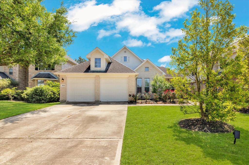 Charming single-story home with a welcoming driveway leading to a two-car garage. The front yard is beautifully landscaped with lush greenery and mature trees, enhancing curb appeal. The house features a gabled roof and a well-maintained exterior, perfect for a cozy family living.