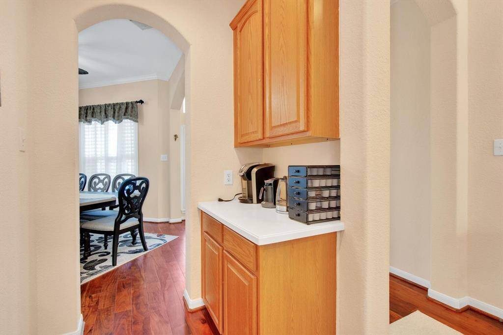 Cozy hallway with warm wood flooring, leading to a dining room. The hallway features butler pantry.