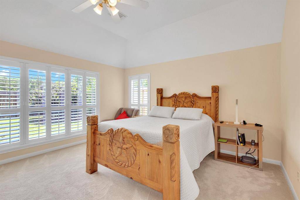 High ceilings, large windows with shutters. The neutral walls and carpet create a warm and inviting atmosphere.