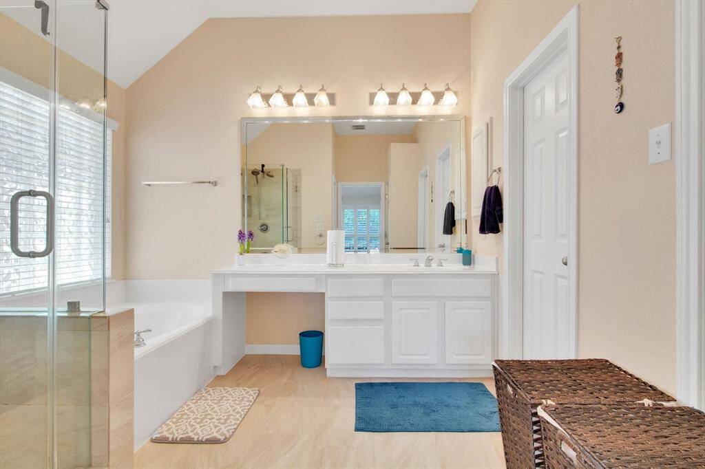En-suite bathroom features a spacious layout with a glass-enclosed shower, a large jetted tub, and vanity with ample counter space. Neutral tones and natural light create a serene atmosphere.