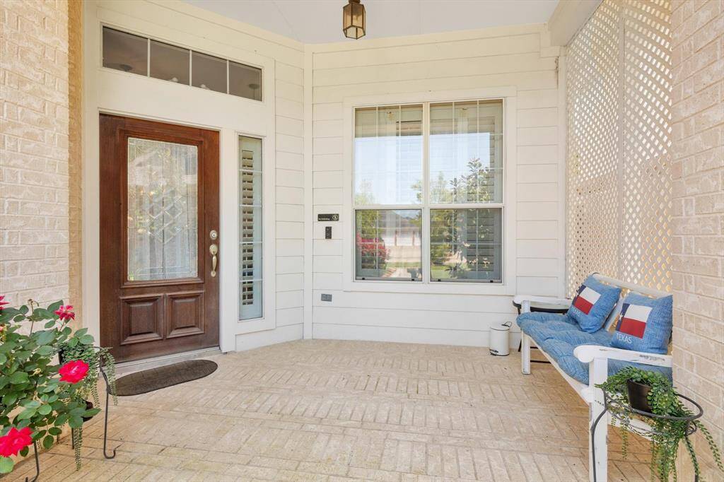 Inviting private front porch, wooden front door with glass panels. The space is bright and welcoming, perfect for relaxing or greeting guests.