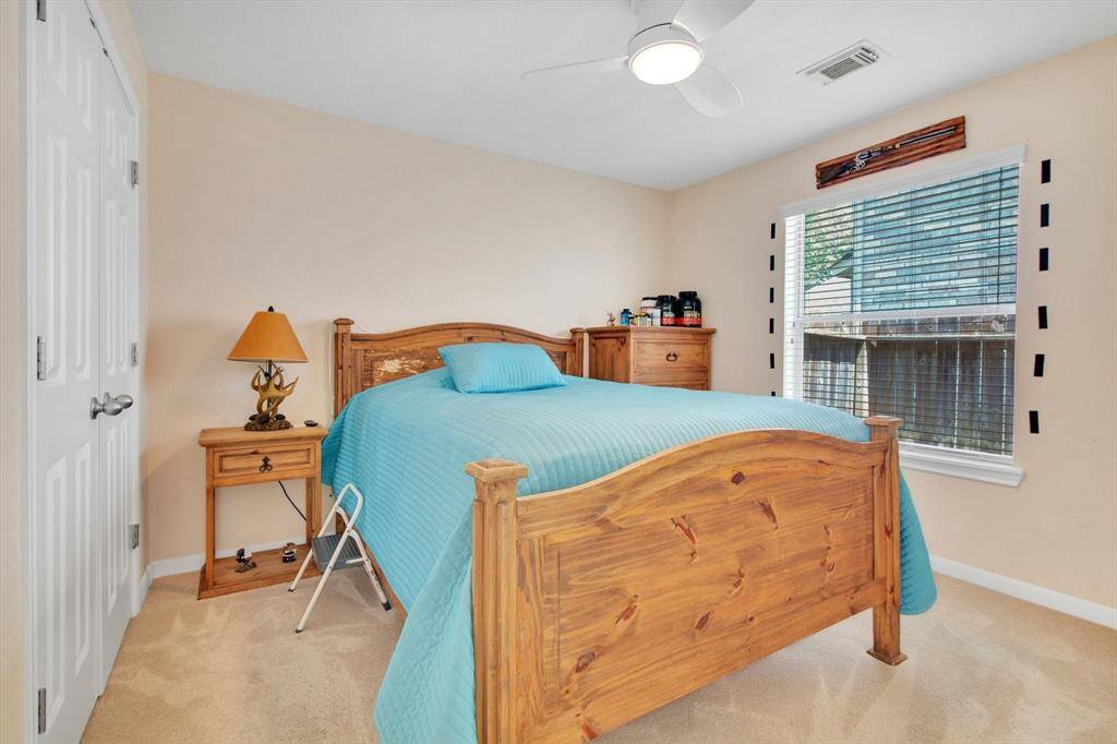 Cozy bedroom with a ceiling fan, large window for natural light, dual closet doors and neutral walls.
