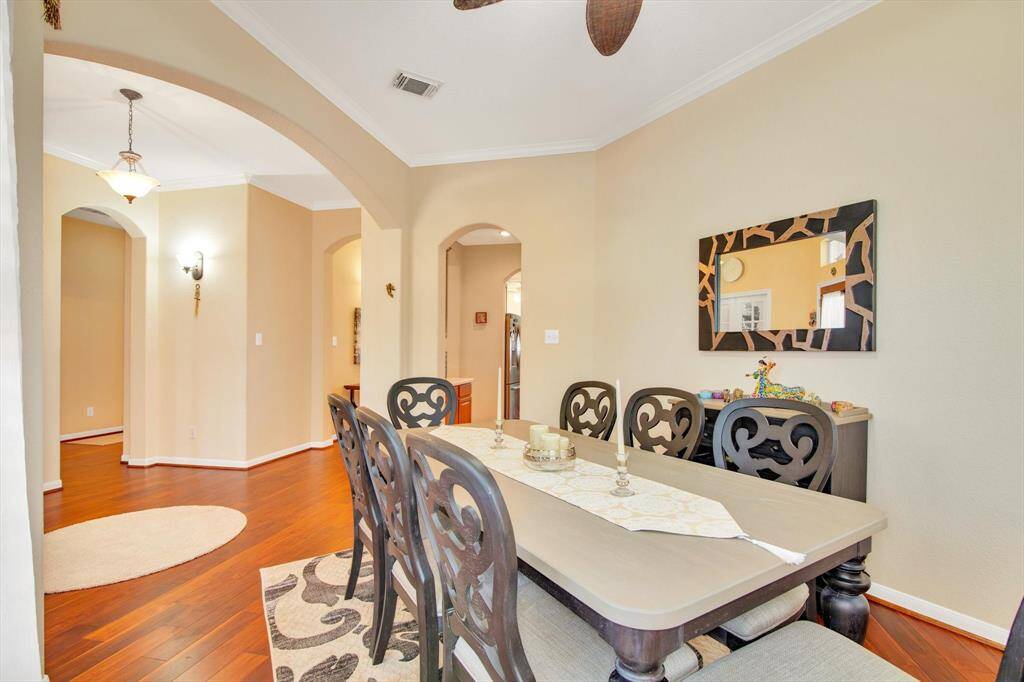 Bright dining room with elegant wooden flooring, archways, and neutral-toned walls.