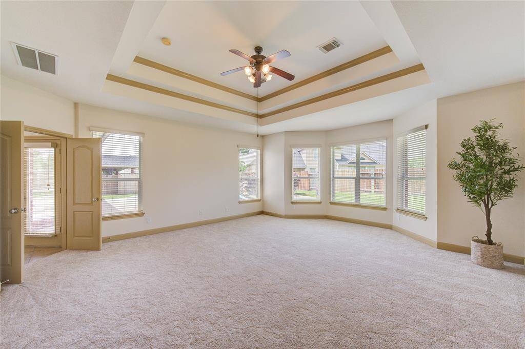 Spacious bedroom featuring elegant double crown molding, soaring vaulted ceilings, and brand-new carpeting.