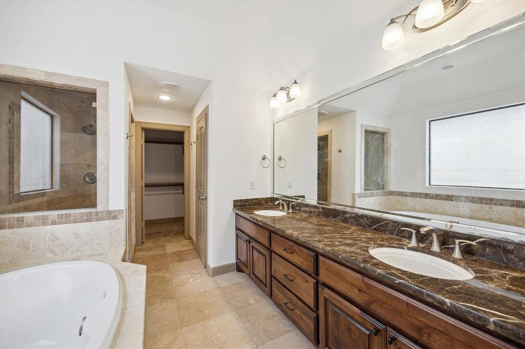 Enter through double doors into primary bath retreat with dual counters, seamless shower and soaking tub.
