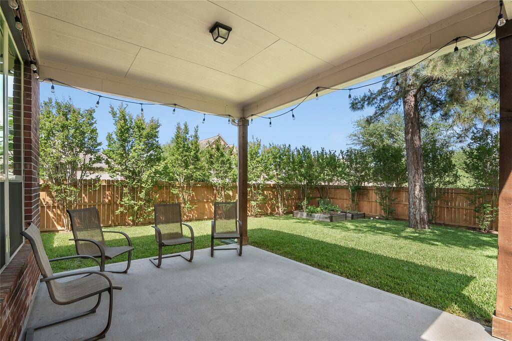 Spectacular covered back porch with a view of this peaceful backyard.