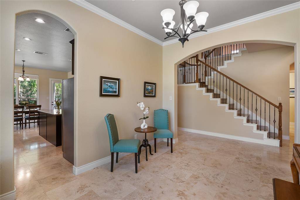 Dining room with distinguished travertine flooring, crown moldings and elegant lighting fixtures.