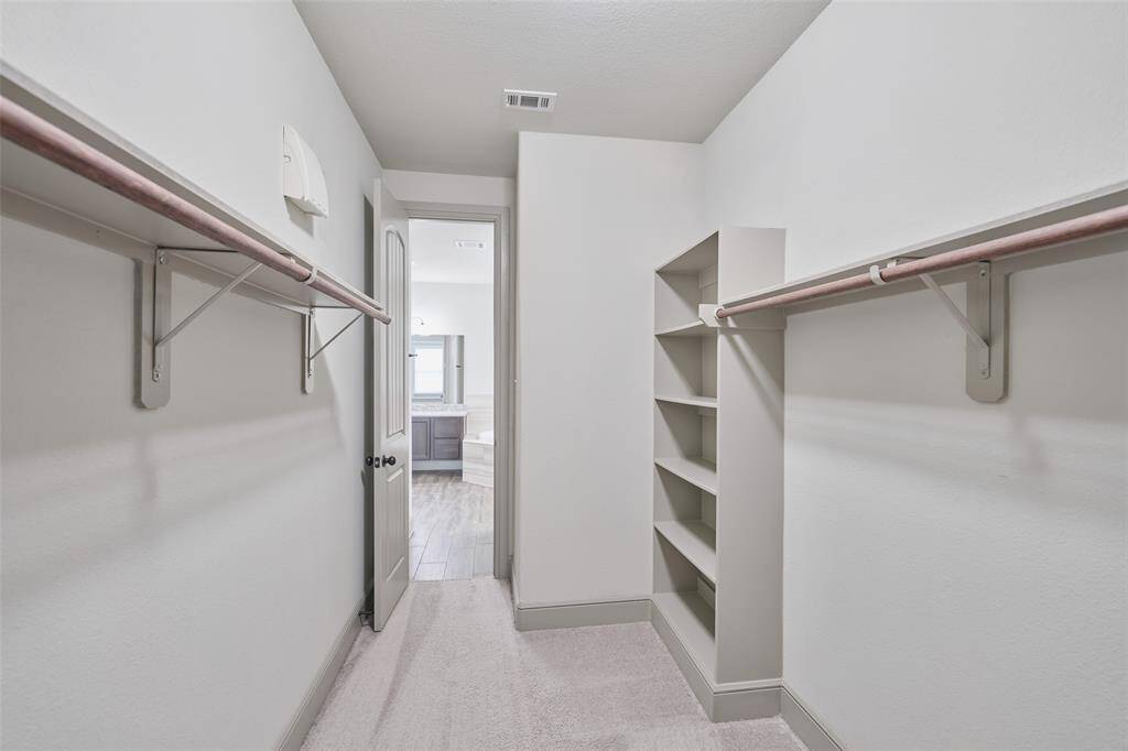 Primary closet with view towards bath.