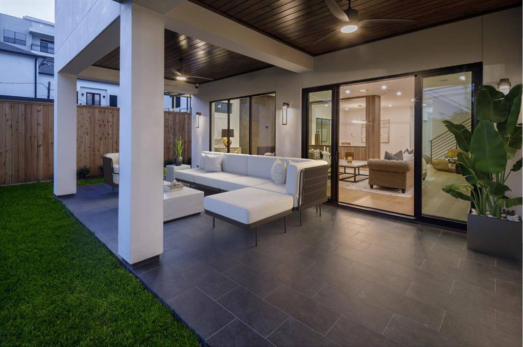 Outdoor covered deck looking into the living area through large glass sliding doors.  Photo is virtually staged