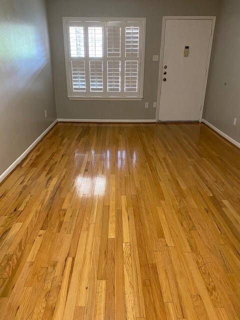 This is an old picture before the tenant moved in. This room features laminate floors and a large window with shutters for natural light. The space is bright and inviting, ideal for a cozy living area.