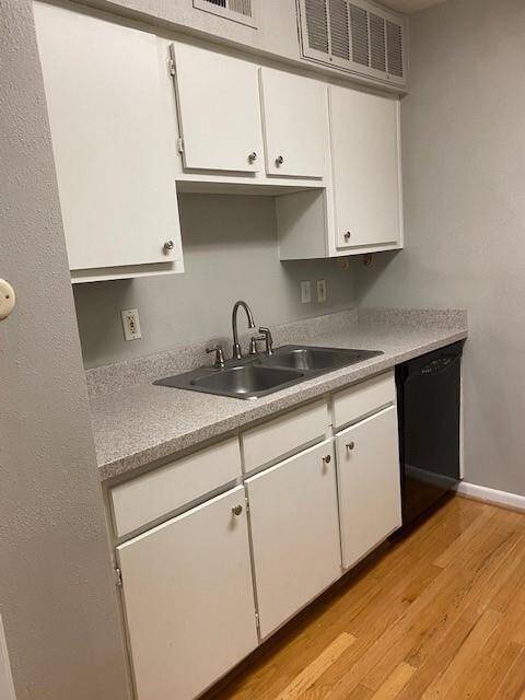 This is an old picture before the tenant moved in. The kitchen features white cabinetry, a double stainless-steel sink, and light gray countertops. It also has a built-in dishwasher, creating a clean and functional space.