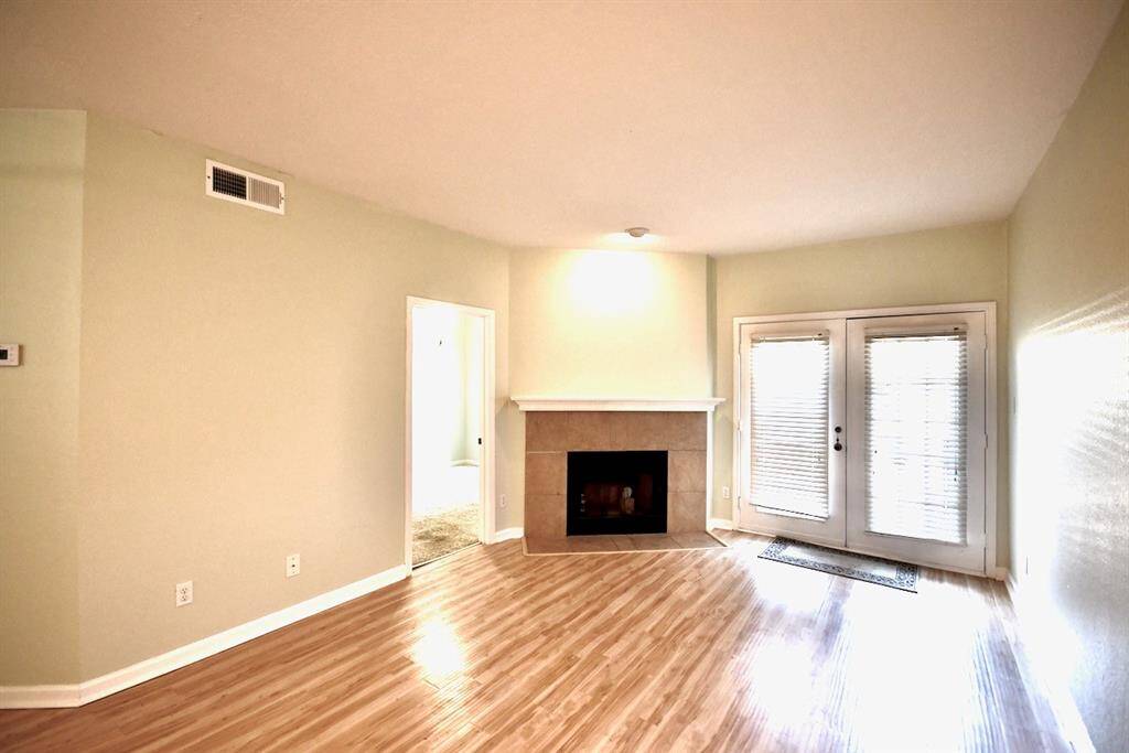 Spacious living area centered around a beautiful fireplace, perfect for entertaining or cozy nights in. Elegant double French doors lead out to your own private patio, creating a seamless indoor-outdoor living experience.