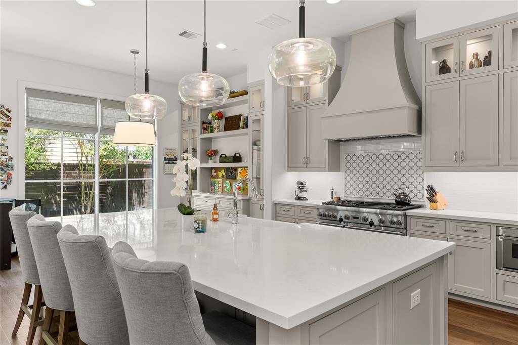 Pendant lighting, Wood paneled Thermador Vent hood, Glass front upper cabinets w/ lighting.