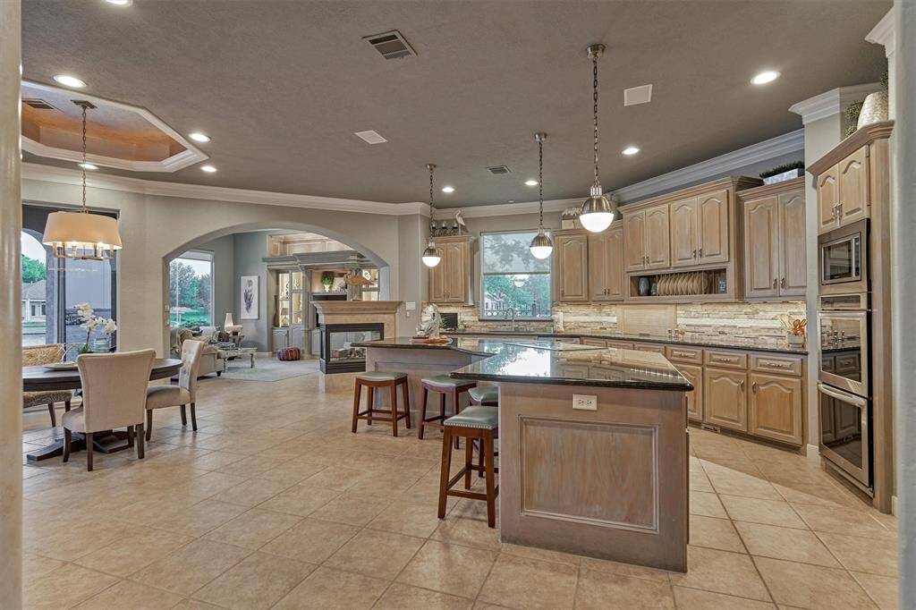 This spacious kitchen offers plenty of room for meal preparation, cooking, and entertaining. Featuring a large center island with a cooktop and extra seating, under-cabinet lighting, double convection ovens, and a built-in microwave—it is everything you need for a chef's dream. Open to the breakfast area and family room, this kitchen is perfect for hosting gatherings with family and friends.