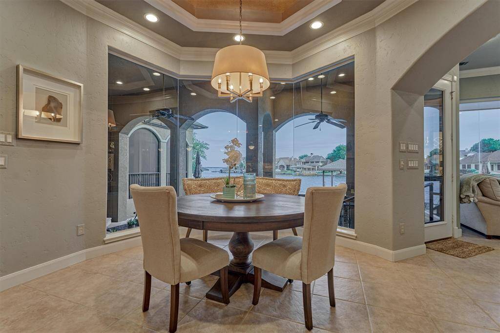 The breakfast area features a seamless glass bay window overlooking the lake—an ideal spot to start your day. Enhanced by a stylish light fixture, crown molding, and a custom ceiling design, this space is rich in architectural detail and charm.