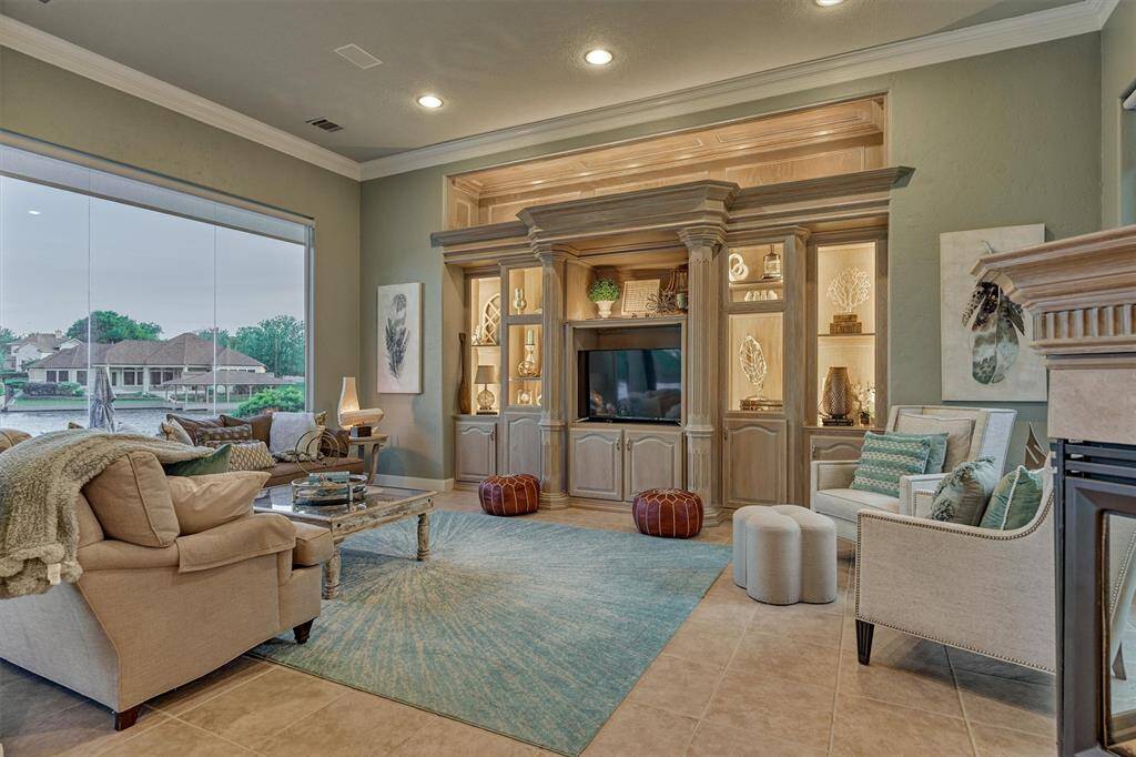 The family room overlooks the lake and features built-in shelving with custom lighting. Expansive butt-glass windows on both sides flood the space with natural light, beautifully framing the serene waterfront views.