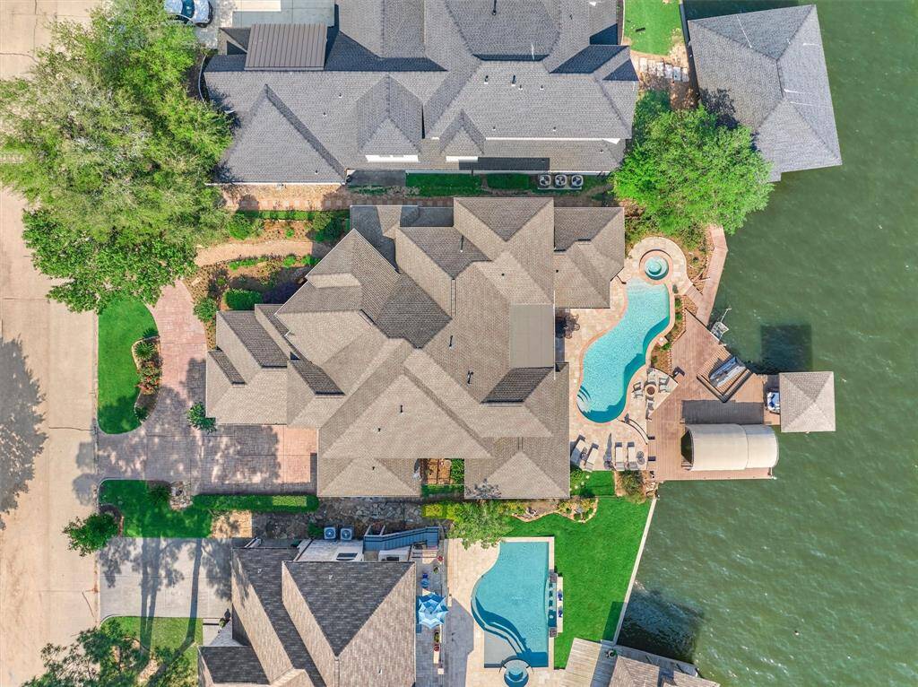 A stunning aerial view captures the home's elegant circle drive, sparkling pool, and expansive lakeside decking—showcasing its impressive layout and prime waterfront location.