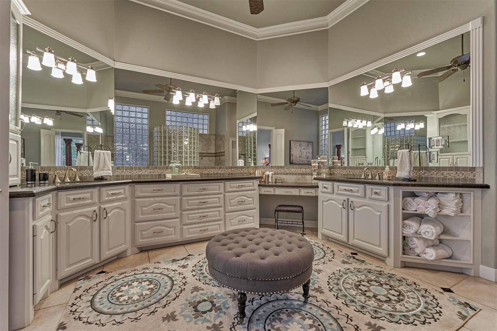 Ample counter space, cabinetry, drawers, and open shelving provide versatile storage options. A framed mirror, enhanced by stylish lighting and coordinating tile, completes the custom-designed look.