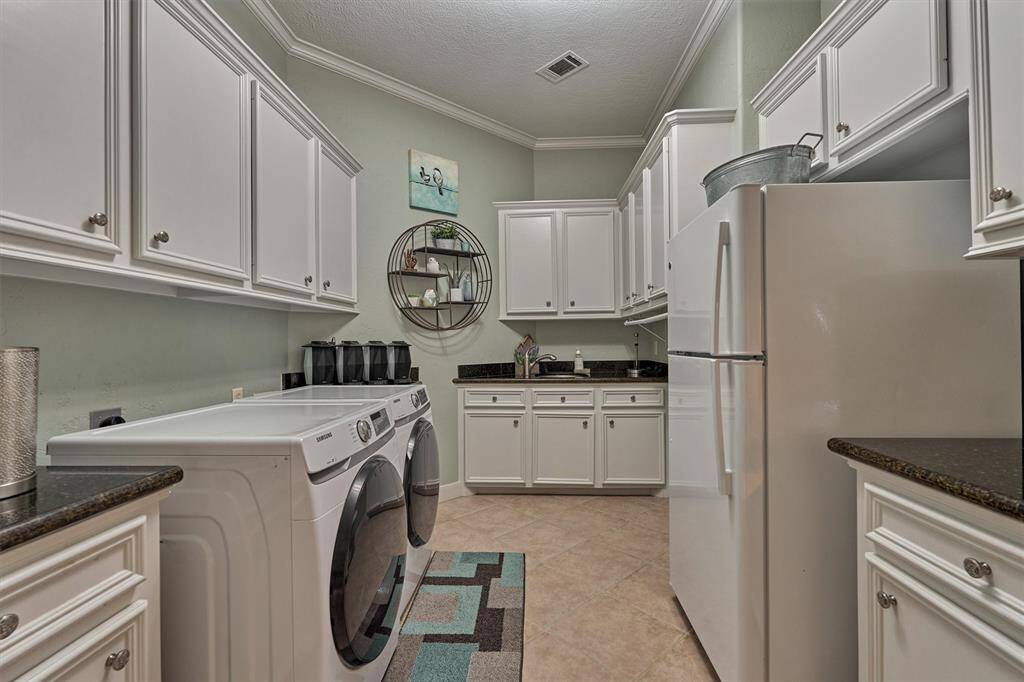 The large utility room has plenty of counter space, abundant storage cabinets and a designated area for a second refrigerator or freezer.