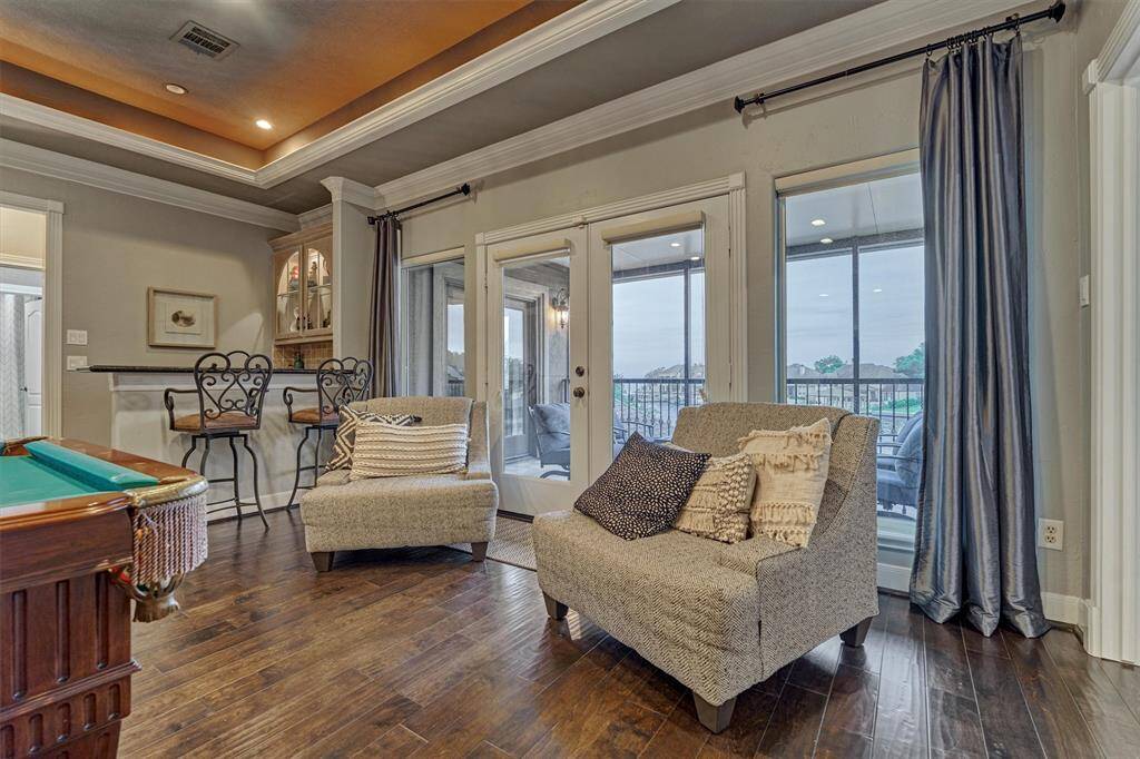 The game room features double doors that open to a screened-in balcony, offering a breezy extension of the living space. A built-in bar area with a beverage refrigerator adds convenience- perfect for enjoying snacks and drinks while relaxing or entertaining.