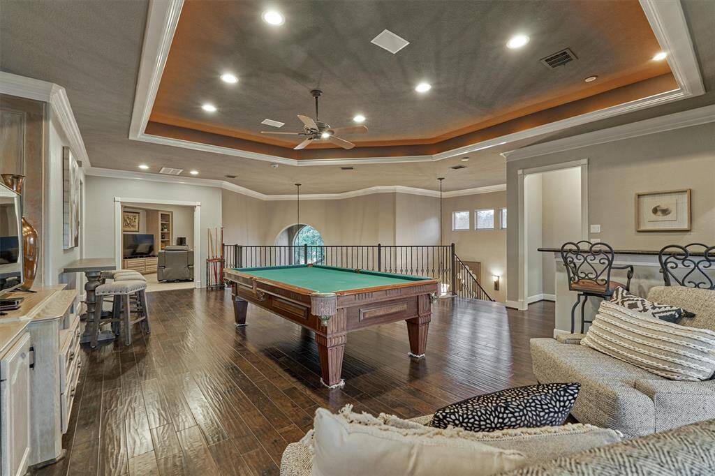 Another view of the game room highlights the tray ceiling with accent lighting and offers a glimpse of the two-story entry foyer beyond, adding to the home's open and elegant feel.
