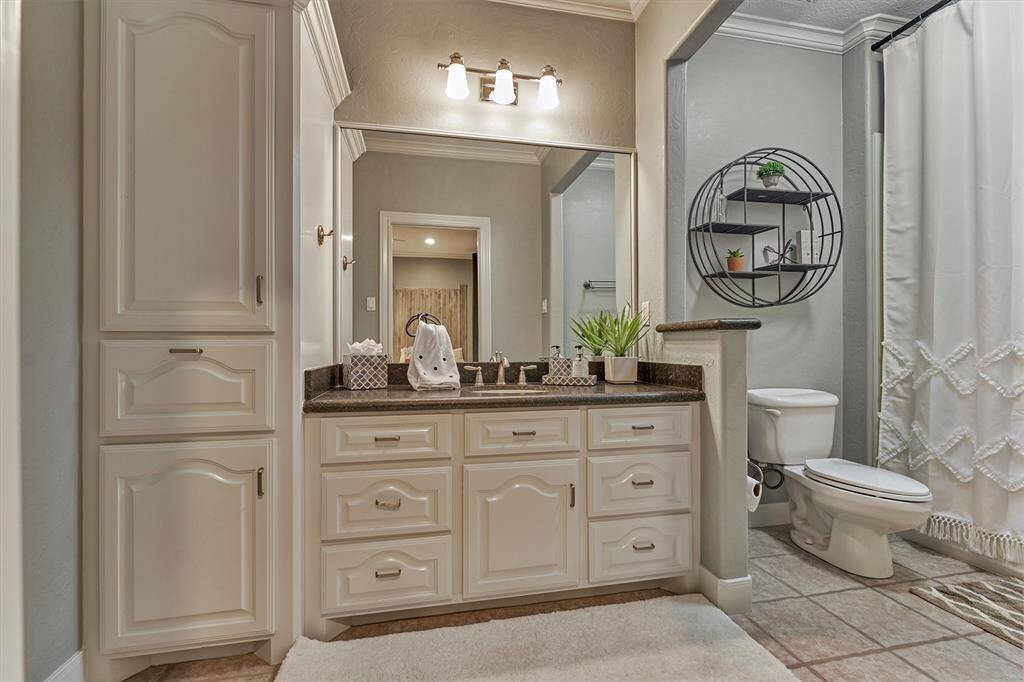 The en-suite bath for the first guest room includes a spacious vanity, storage cabinets and drawers and a tub and shower.
