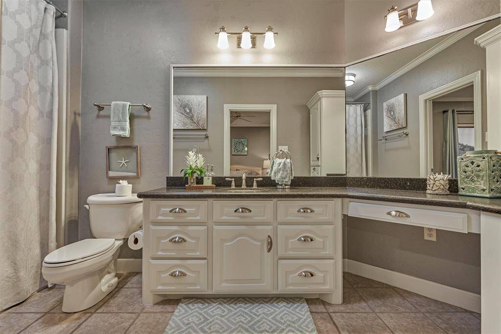 This en-suite bath offers a designated vanity area, abundant storage for toiletries and towels, and a combination tub and shower.