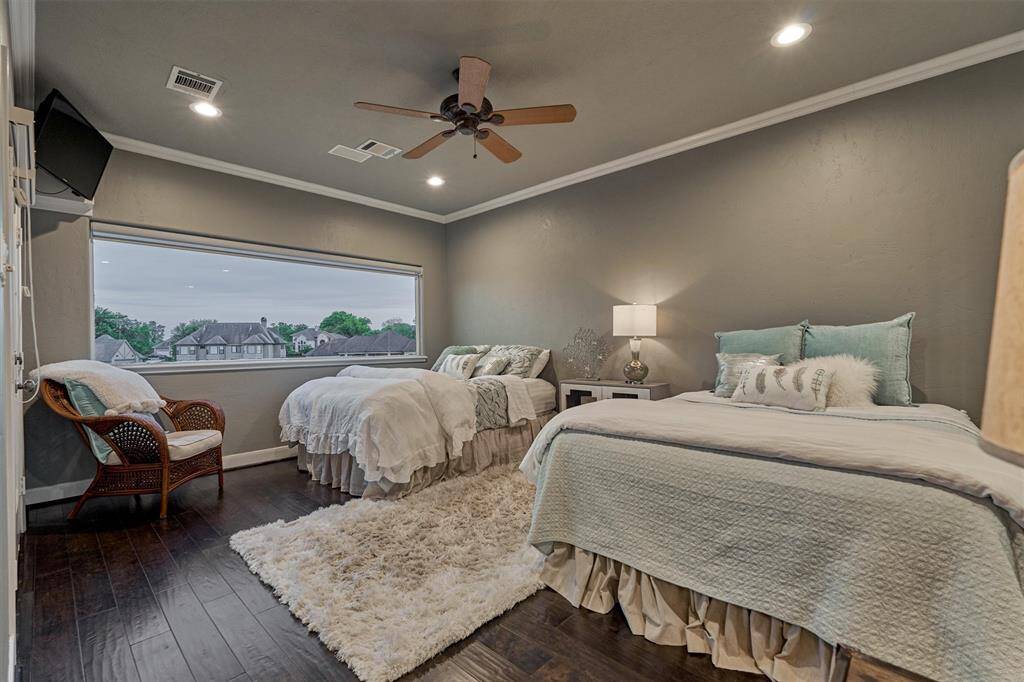 A versatile bonus room, currently set up as the fifth bedroom, showcases a large picture window with captivating views of the lake and pool area. Double doors open to the screened-in balcony.