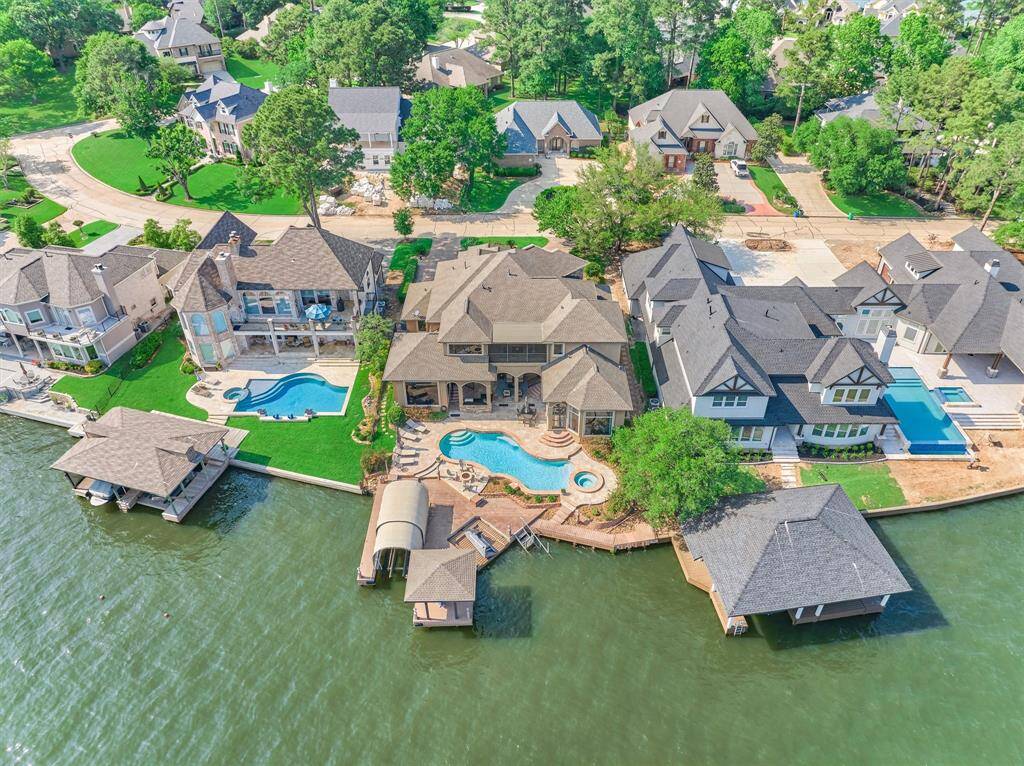 A rear view of the home showcases the expansive decking surrounding the pool and extending to the lake, providing abundant space for outdoor entertaining and relaxation.