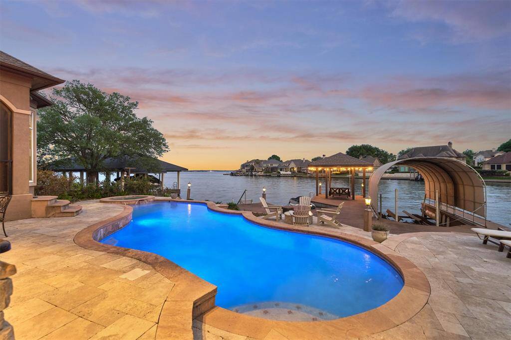 Enjoy the outdoors with a sparkling pool and hot tub, ample decking for multiple seating areas, a private boat slip with lift, and a cozy fire pit- perfect for entertaining or unwinding by the water.