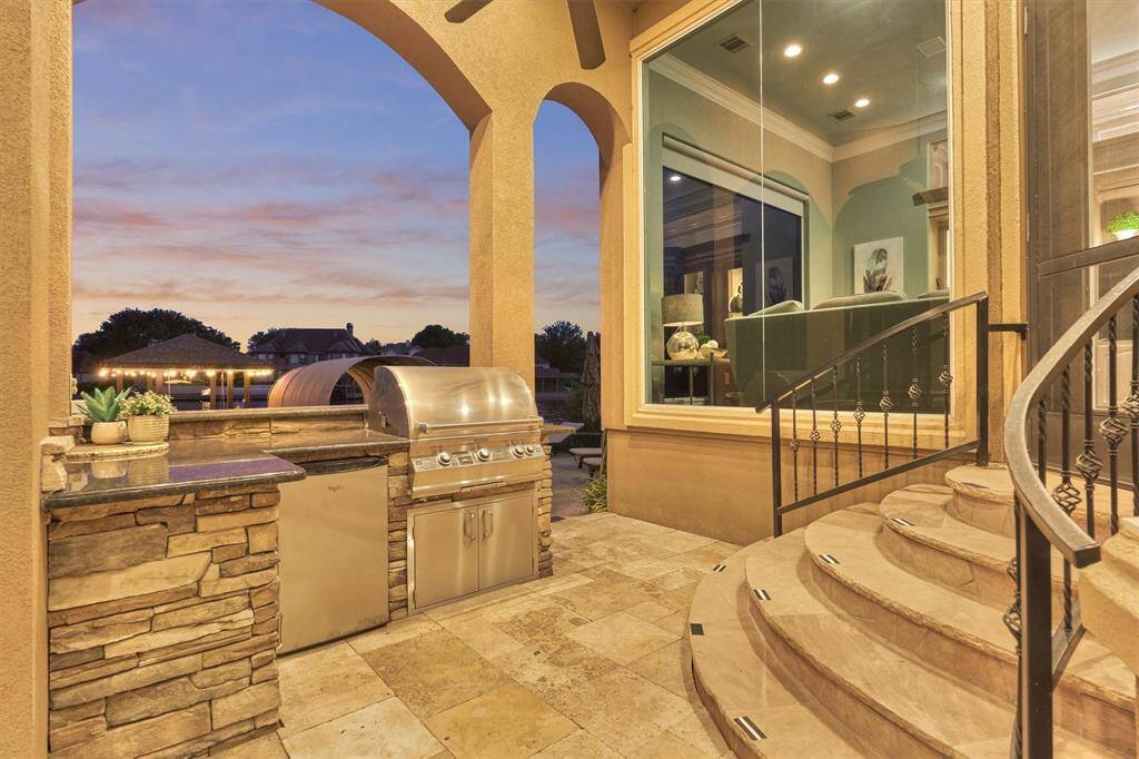 The outdoor kitchen is fully equipped with a gas grill, sink, and beverage refrigerator, creating the ultimate space for outdoor entertaining and lakeside dining.