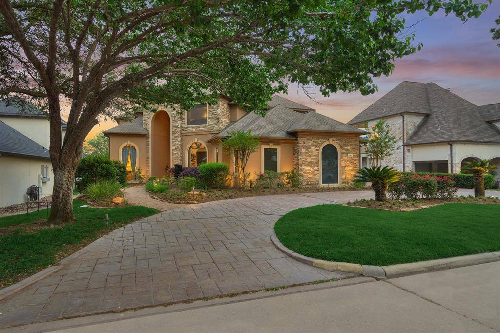 A stamped concrete circle drive offers elegant and convenient parking for residents and guests. Thoughtfully placed landscape lighting beautifully highlights the home's stucco and stone exterior, enhancing its curb appeal both day and night.