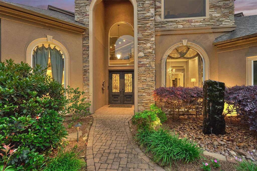 An elegant covered entry welcomes you with a charming stone walkway and meticulously maintained, lush landscaping.